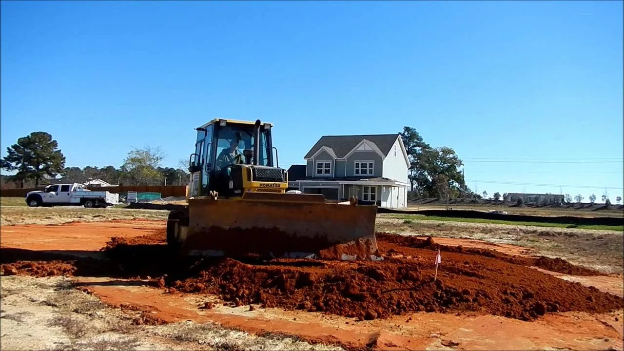 Dozer spreading red clay fill dirt across a new home lot
